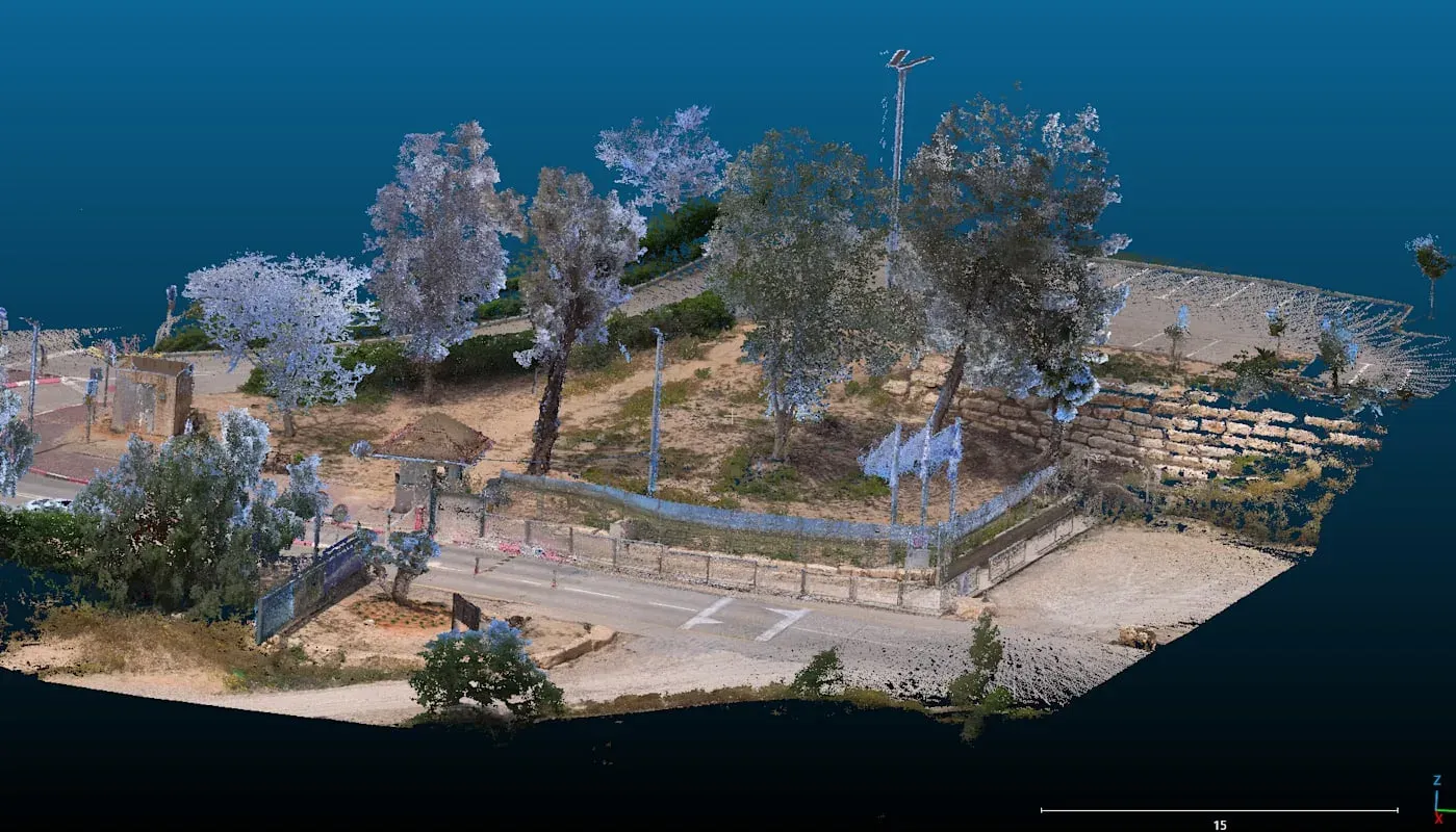 Coloured point cloud of a street corner: kerb, road markings, boundary wall, fencing and trees rendered as millions of measured points.